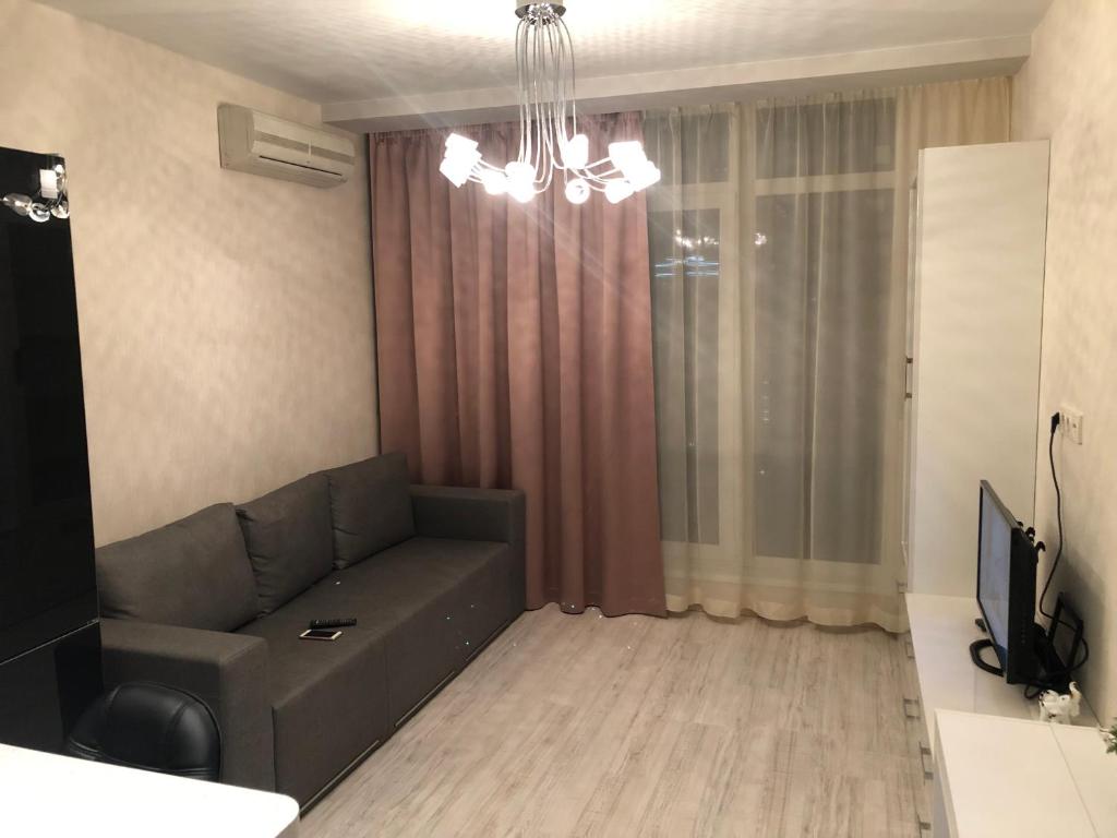 a living room with a couch and a television at Нова затишна квартира Студіо плюс спальня біля метро Житомирська in Kyiv