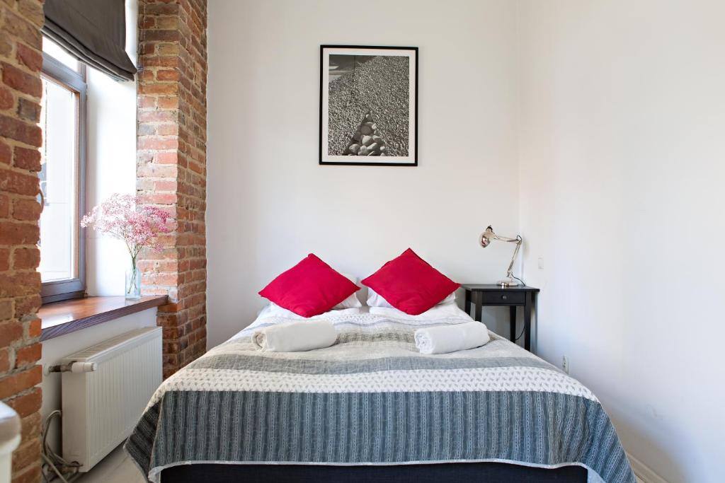 1 dormitorio con 1 cama con almohadas rojas en Apartamenty Królewska, en Lublin