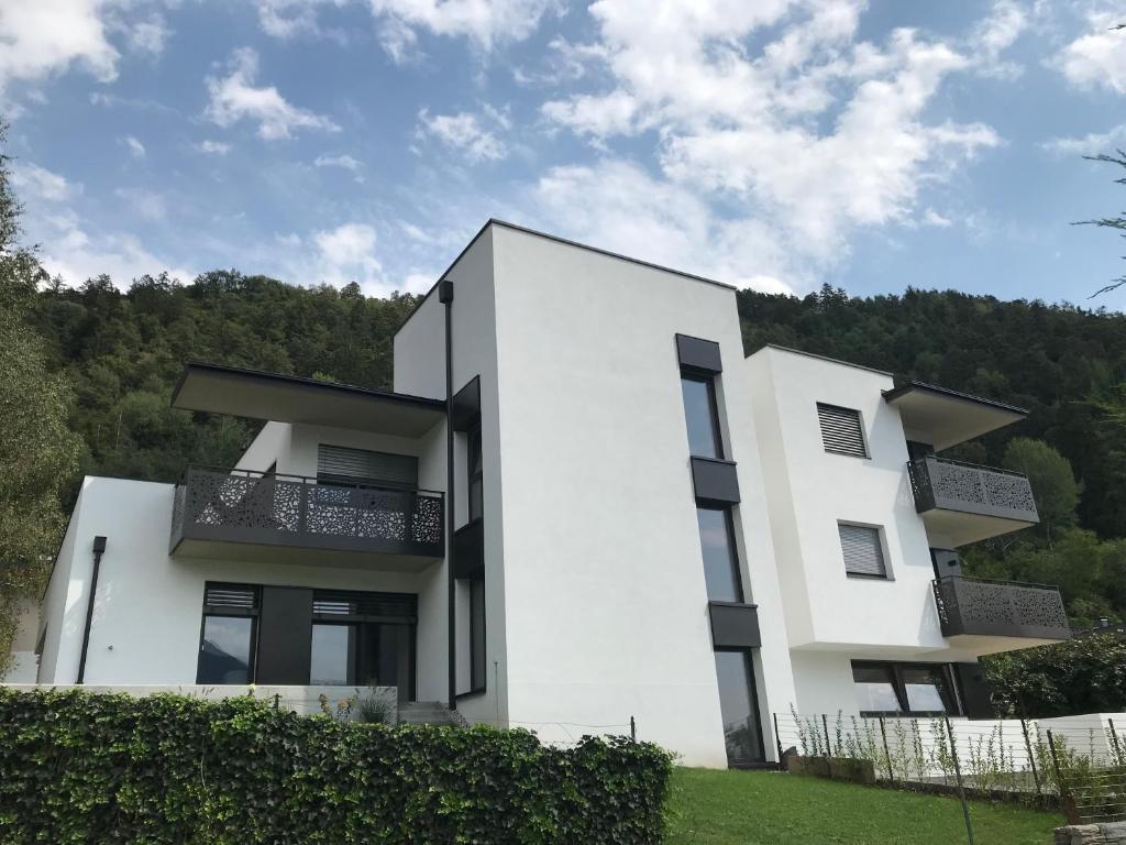 ein weißes Haus mit Bäumen im Hintergrund in der Unterkunft Apartment42 in Brixen