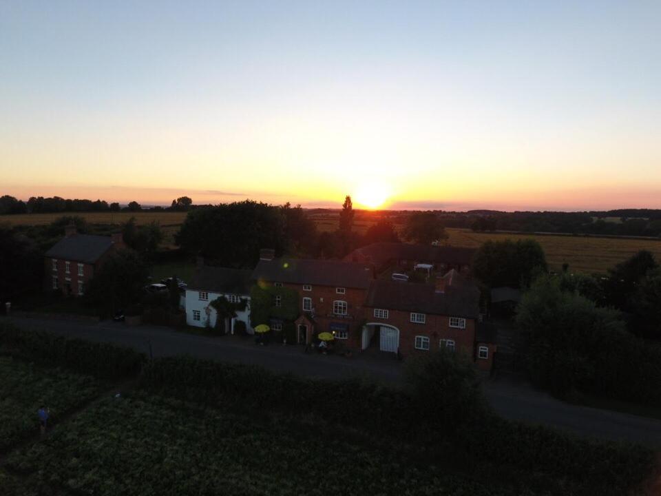 een zonsondergang boven een stad met huizen in een veld bij The Royal Arms Hotel in Sutton Cheney