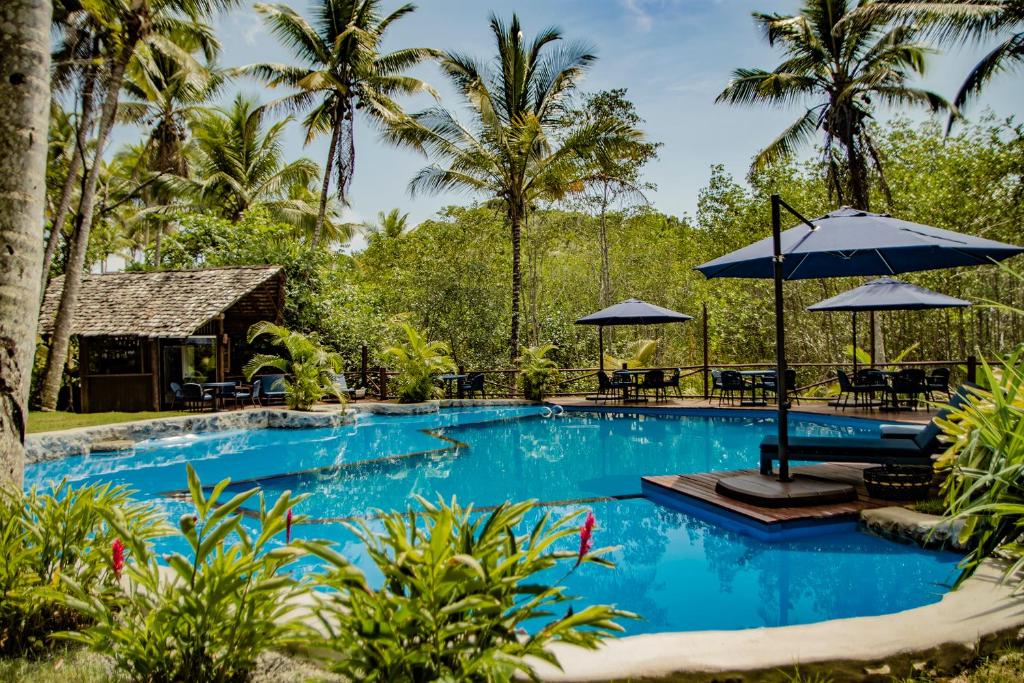 una piscina en un complejo con sillas y sombrillas en Itacaré Eco Resort en Itacaré