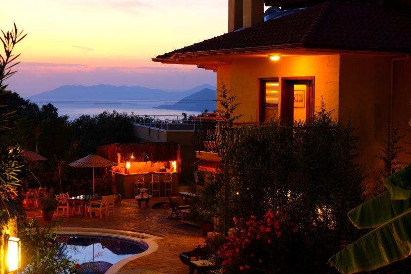 a house with a swimming pool in front of a sunset at Mandarin & Mango Boutique Hotel in Faralya