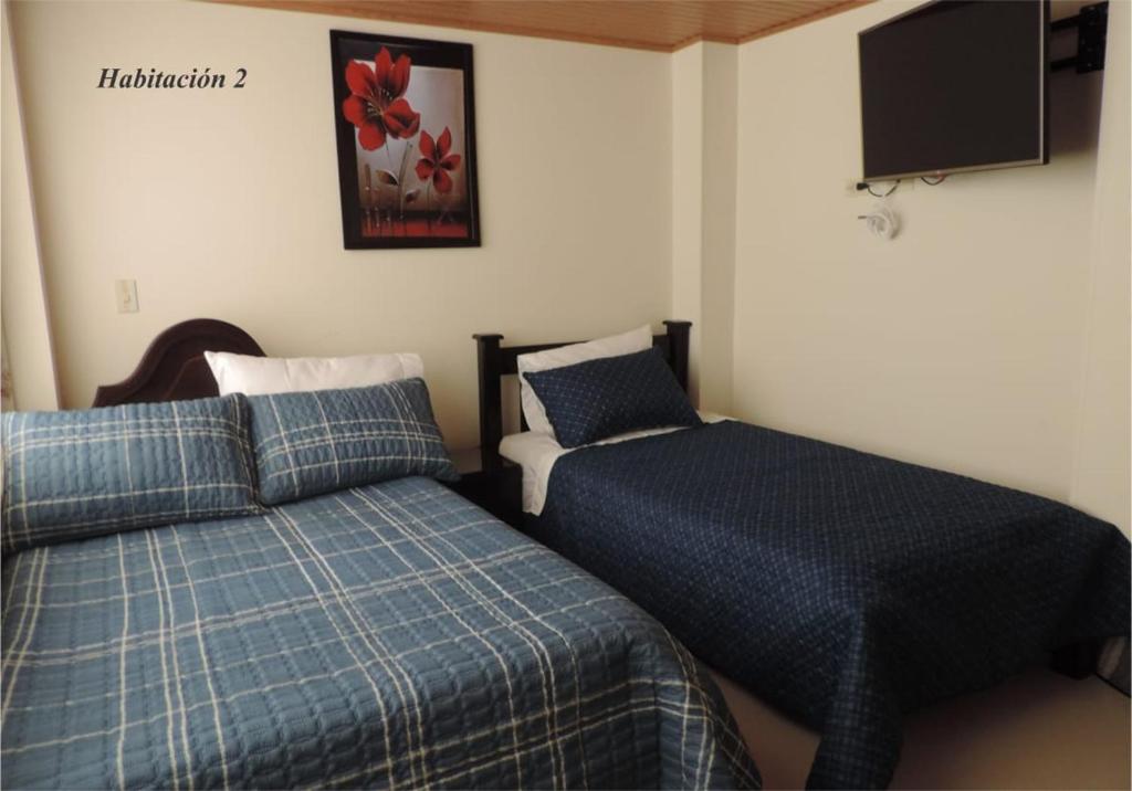 a bedroom with two beds and a flat screen tv at Sueños Vividos Hospedaje in Sogamoso