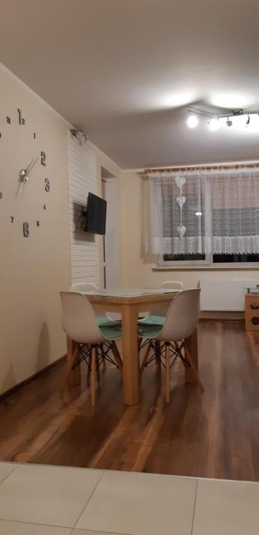 mesa de comedor con sillas y reloj en la pared en Apartament w Suwałkach, en Suwałki