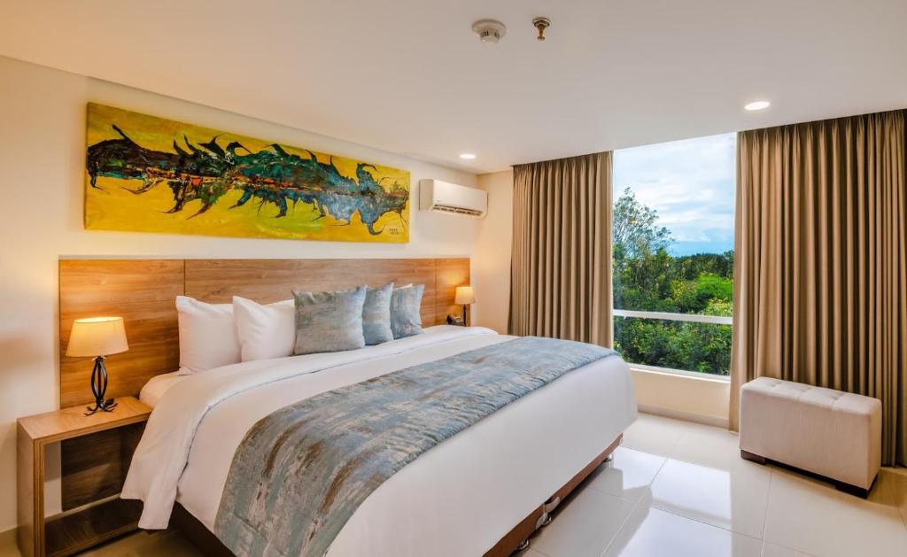 a bedroom with a large bed and a large window at Ambar Hotel Boutique in Cali