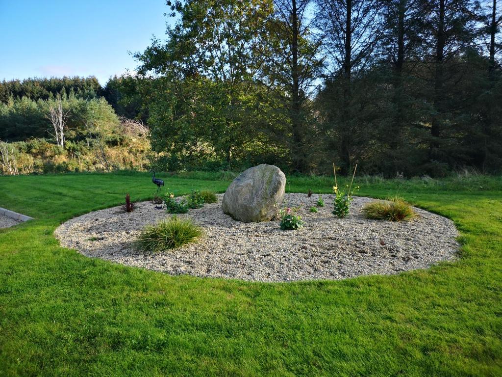 a garden with a large rock in the grass at Forest Path luxury Studio Apartment with large bedroom bathroom and sauna Sleeps up to 4 in Ballynahinch