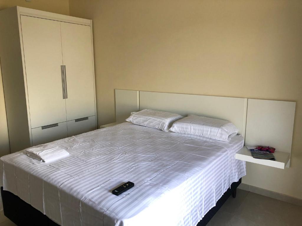 um quarto com uma cama grande e lençóis brancos em Chalés Polinésia em Touros