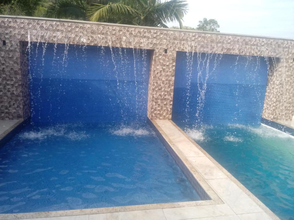 ein großer Pool mit Wasser, das hineinfällt in der Unterkunft Da Silva Chalé in Santa Lídia