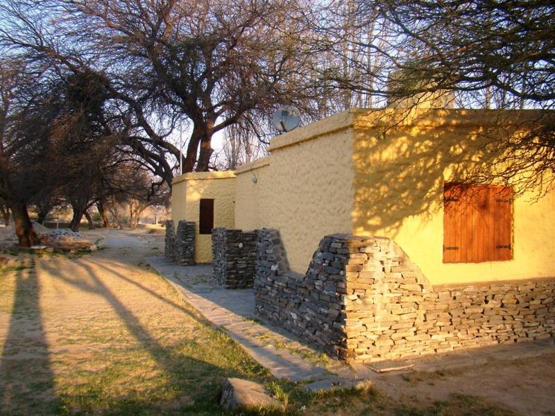 a building with a stone wall next to a tree at Cabañas Achalay in Santa María