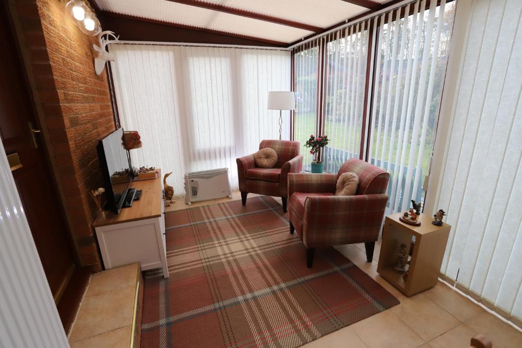 a living room with two chairs and a television at Tweedbank in Galashiels
