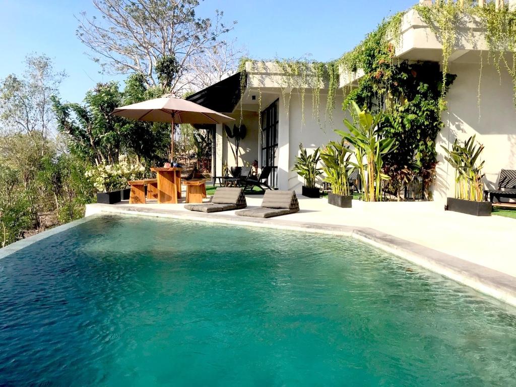 
a patio area with a pool, chair, and umbrella at OCEANNA - Uluwatu, Bali in Uluwatu
