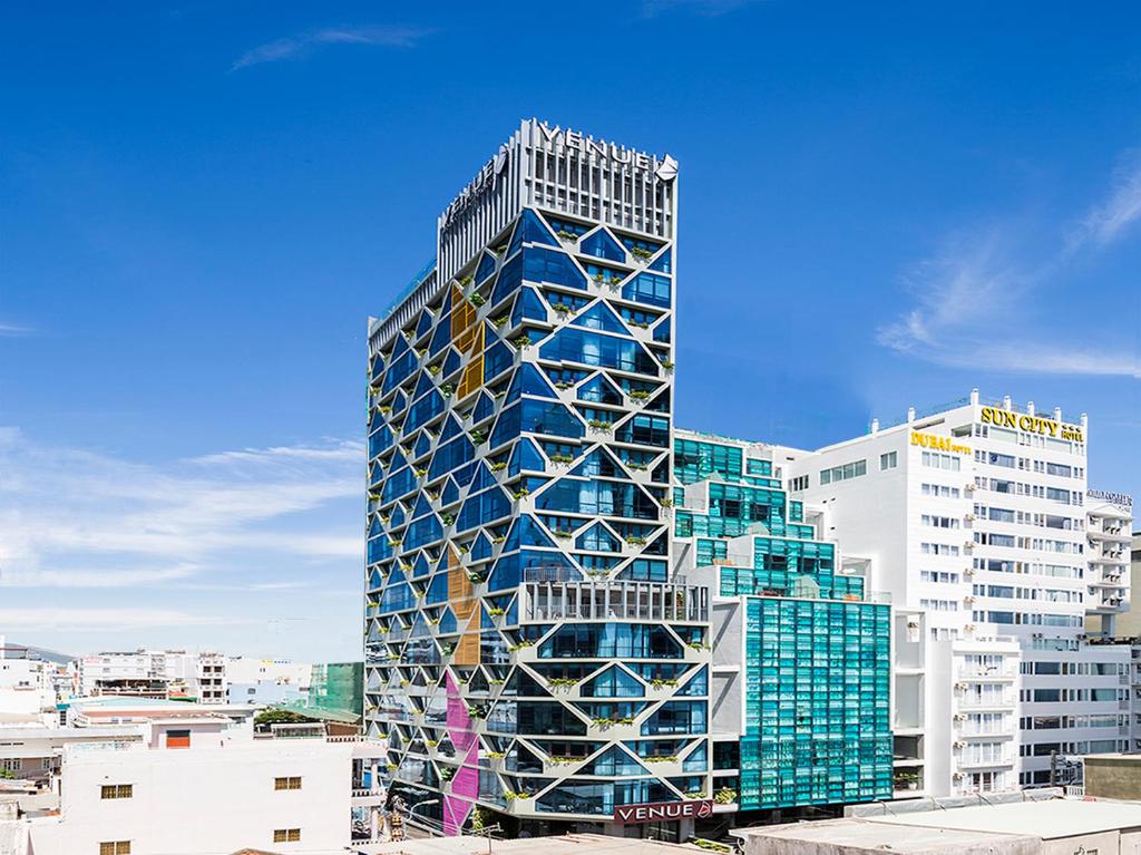 a tall building with glass windows in a city at Venue Hotel Nha Trang in Nha Trang