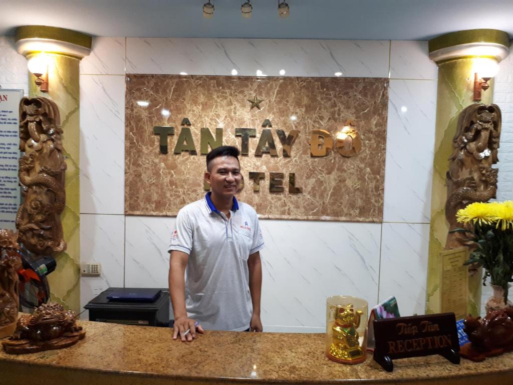 um homem parado em frente a um balcão numa loja em Tan Tay Do Hotel em Can Tho