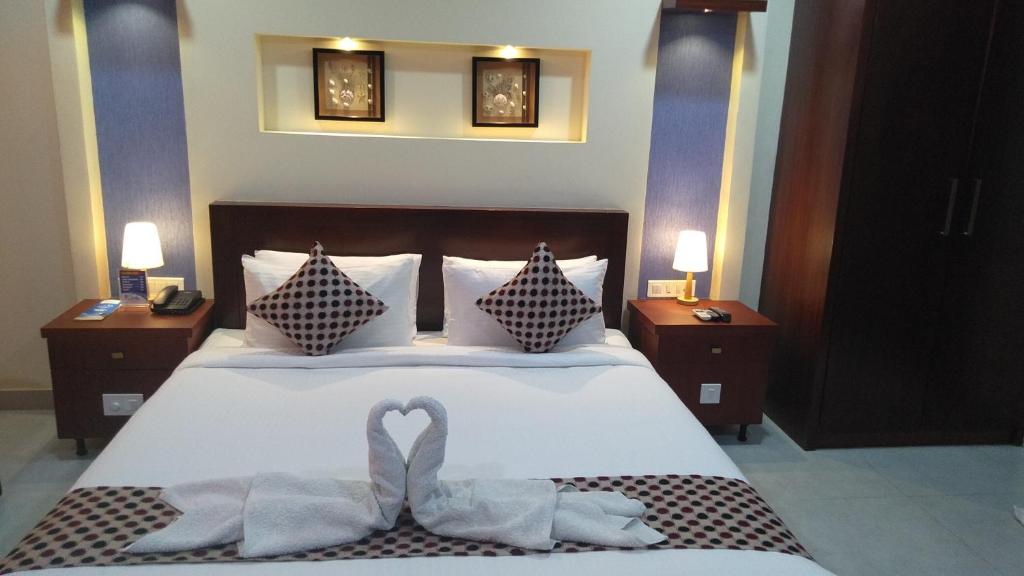 a bedroom with a bed with two swans on it at Rouba Residency Hotel in Ponnāni