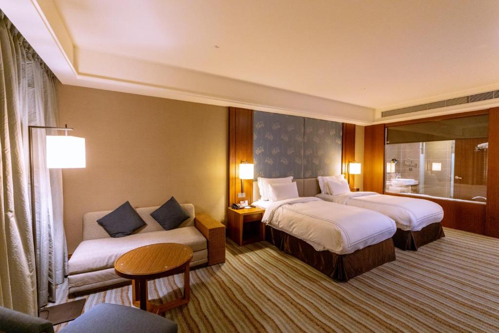 a hotel room with two beds and a couch at Fullon Hotel Tamsui Fishermen&#39;s Wharf in Tamsui