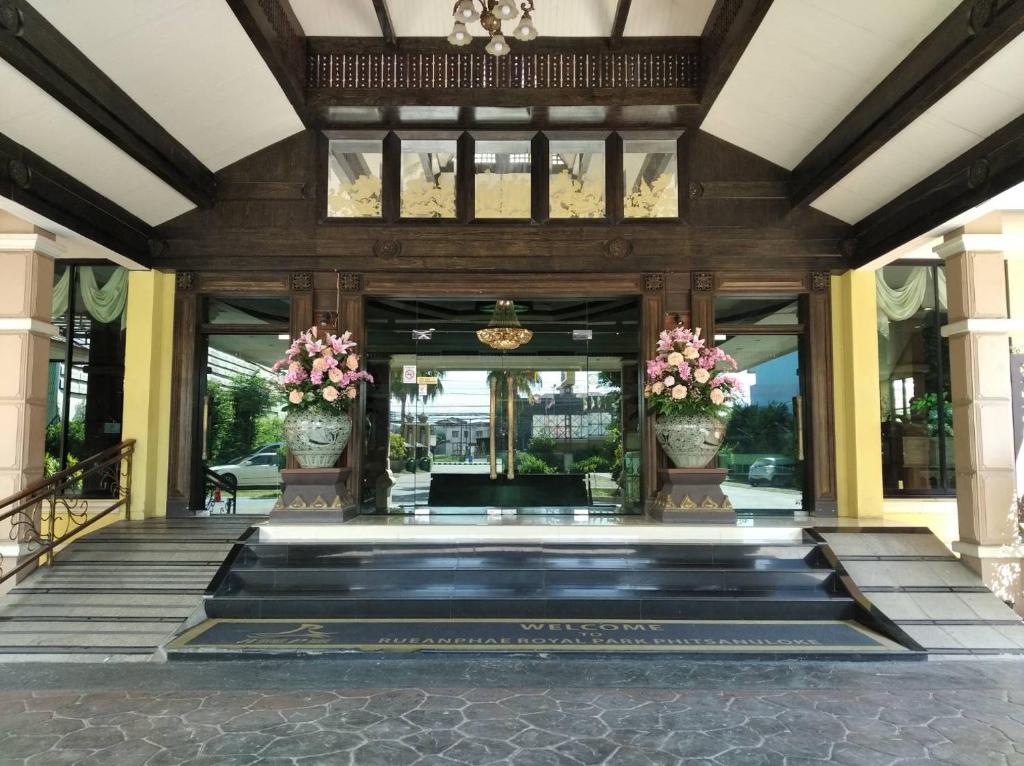 a lobby of a building with two vases with flowers at Ruean Phae Royal Park Hotel in Phitsanulok