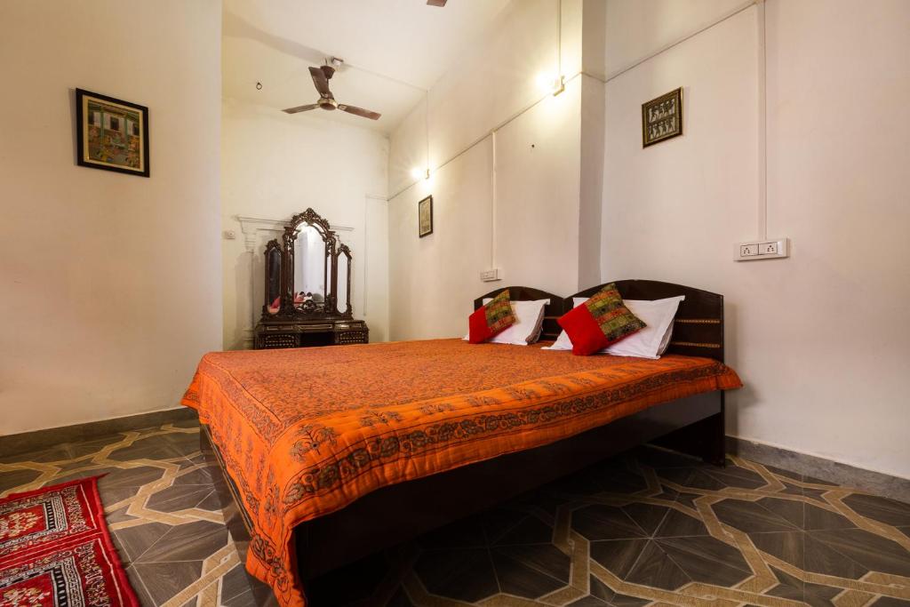 a bedroom with a bed with an orange comforter at Heritage Gouri Haveli in Jodhpur