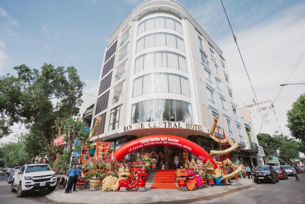 Un grand bâtiment blanc avec un escalier rouge se trouve devant. dans l'établissement Ban Me Central Hotel, à Buôn Ma Thuột