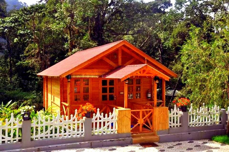 a small wooden cabin with a white fence at Rainforest Munnar in Munnar