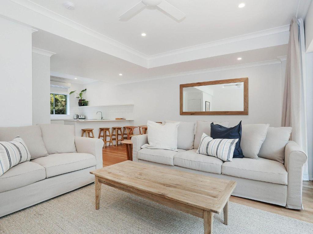 a living room with two white couches and a coffee table at Byron Beachside 8 in Byron Bay