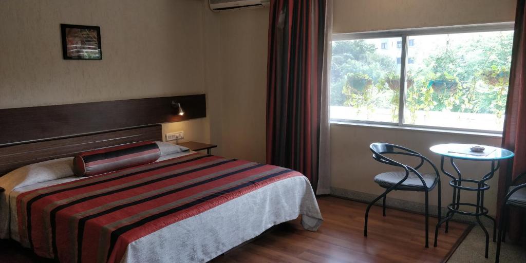 a hotel room with a bed and a table and a window at Nasiklub in Nashik
