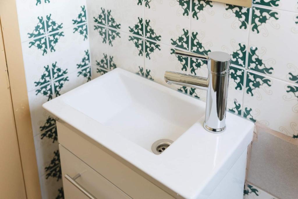 a white sink in a bathroom with green and white tiles at Tropical Loft with View in Volos