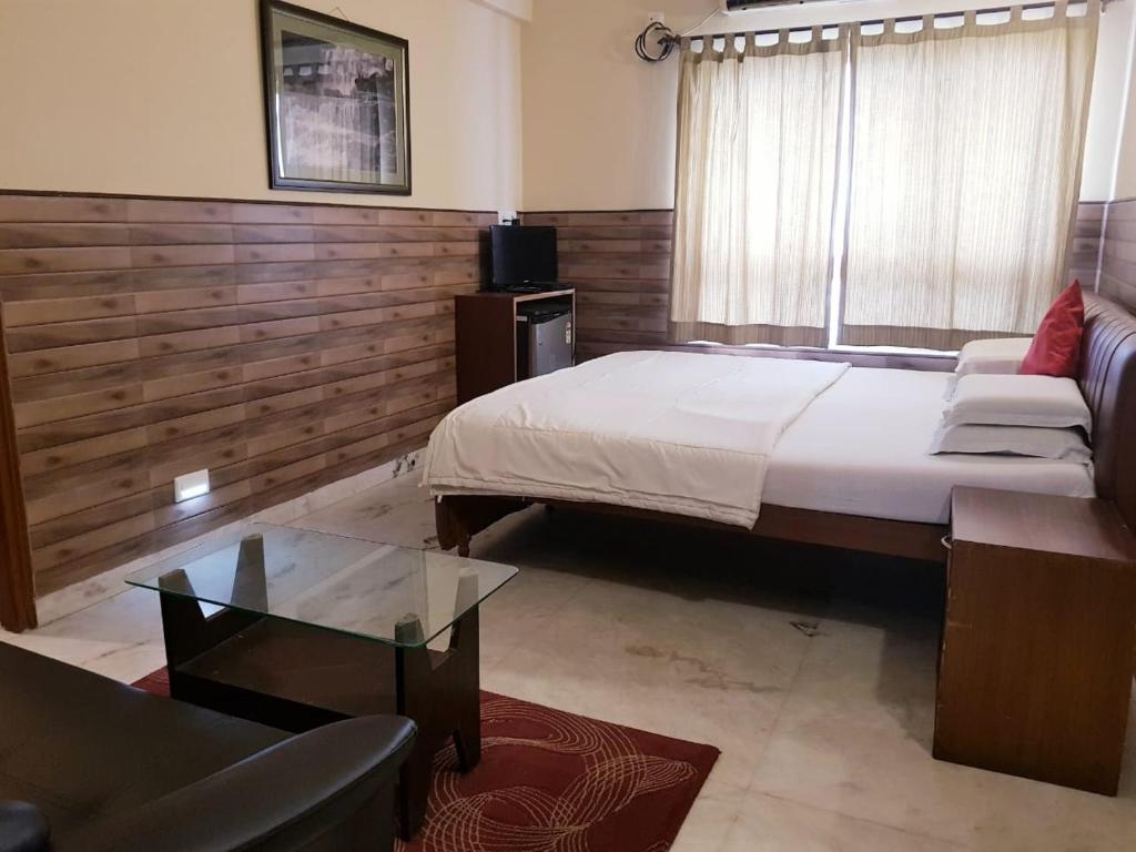 - une chambre avec un grand lit et une table en verre dans l'établissement Malik Guest House, à Kolkata