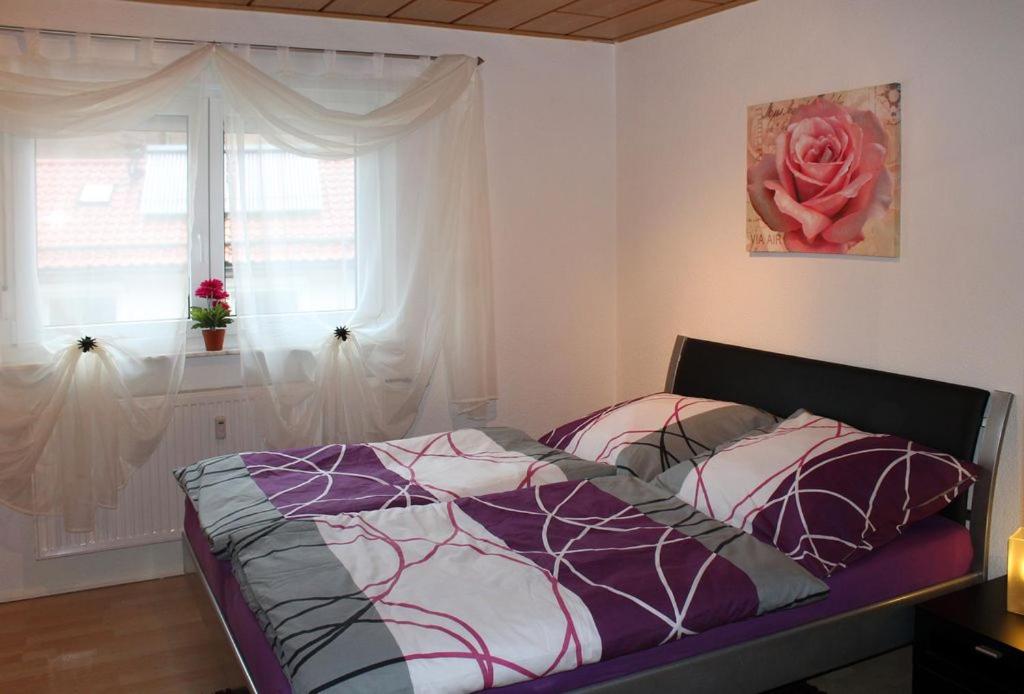 een slaapkamer met een bed en een raam met een roos bij Ferienwohnung Jasmin in Schönau bei Heidelberg Fewo 1 mit Terrasse in Schönau