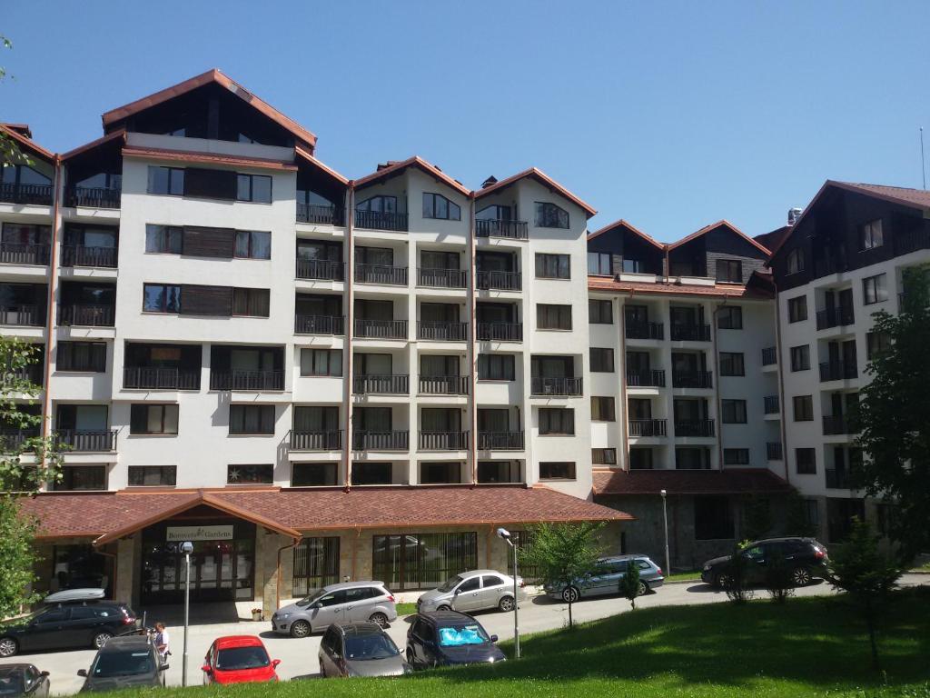 un grande condominio con auto parcheggiate in un parcheggio di Borovets Gardens Apartments TMF a Borovets