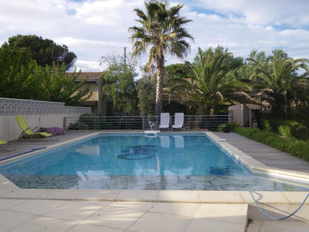 a swimming pool in a yard with palm trees at Les Algues du Grau in Le Grau-dʼAgde