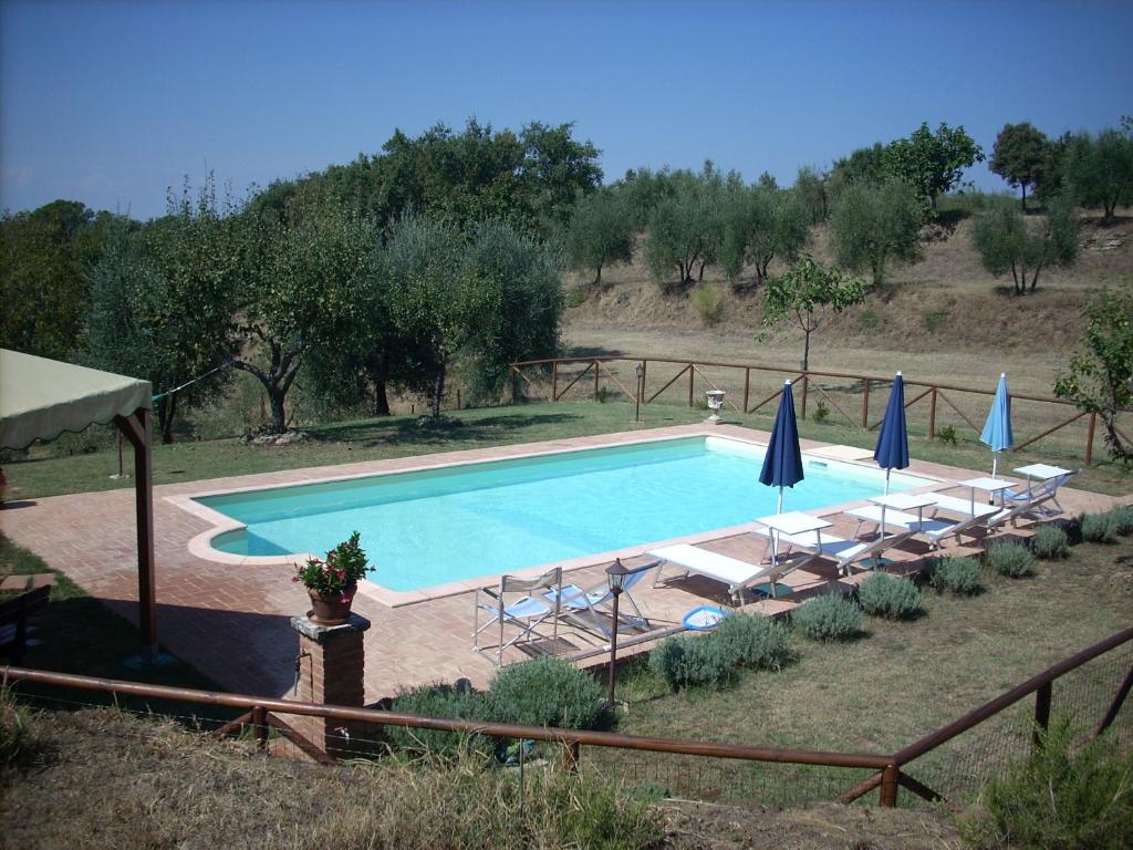 a swimming pool with chairs and umbrellas at PODERE CAPANNE in Sinalunga