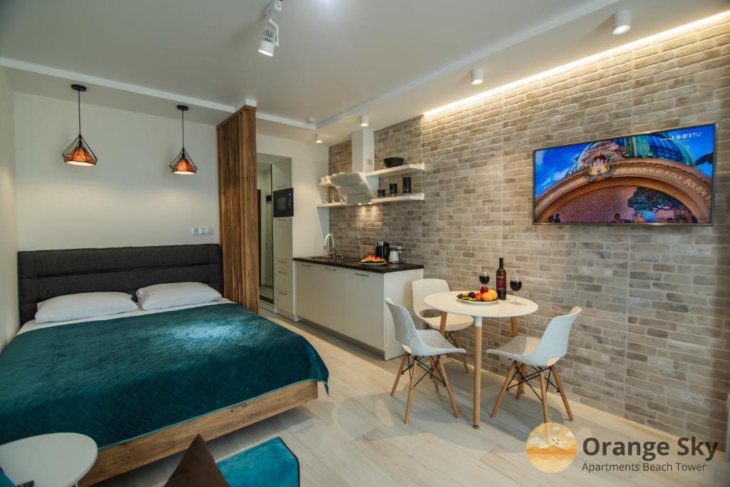 a bedroom with a bed and a table with chairs at Orange Sky Apartments Beach Tower in Batumi