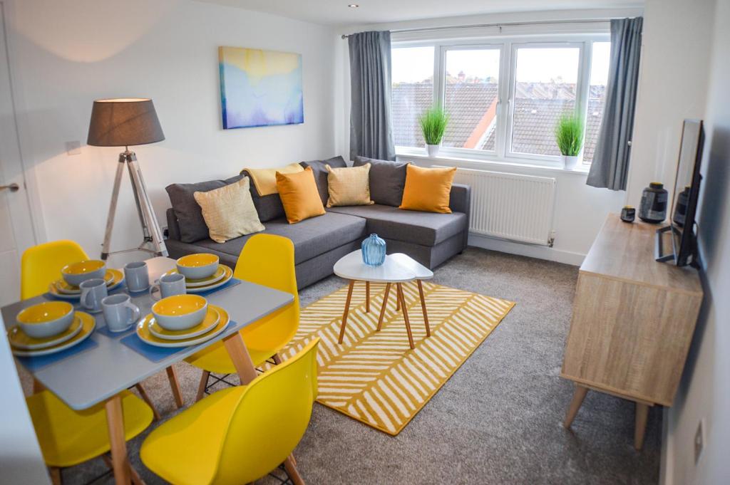 a living room with a couch and a table and yellow chairs at Anstey Heights Apartments in Bristol
