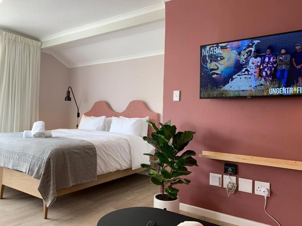 a bedroom with a bed and a tv on the wall at CURIOCITY Green Point in Cape Town