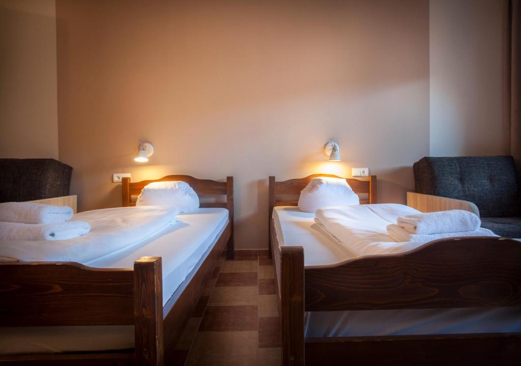 Two single beds in simple room with reading lamps and folded towels, calm neutral tones