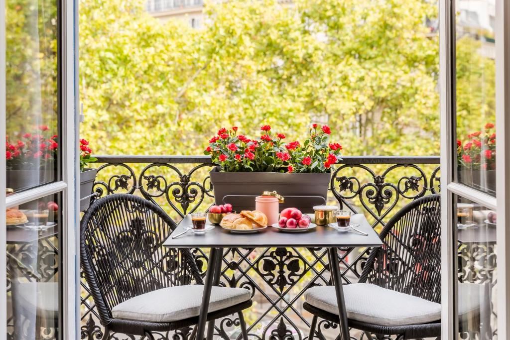 een tafel en stoelen op een balkon met bloemen bij Luxury 2 Bedroom With Balcony - Louvre & Notre Dame in Parijs