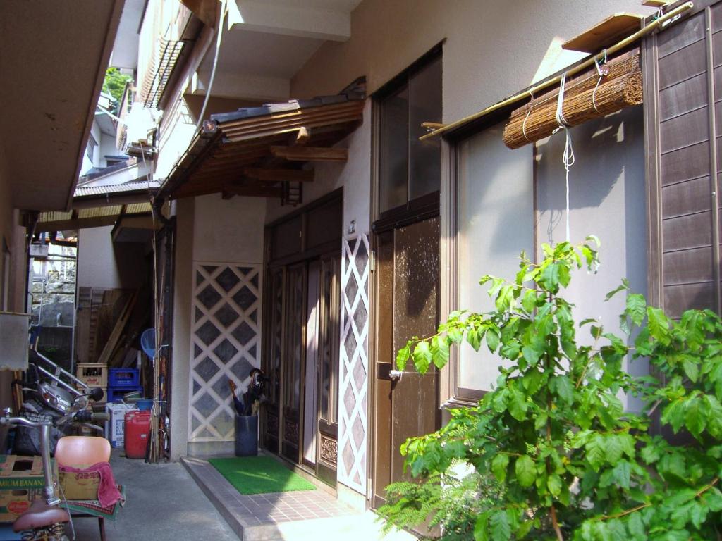 un edificio con una puerta y una planta delante en Ishibu-so, en Matsuzaki