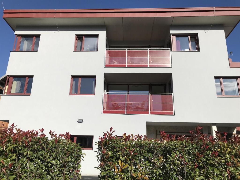 un edificio blanco con ventanas rojas y arbustos en Posthof Apart . Zimmer, en Zirl
