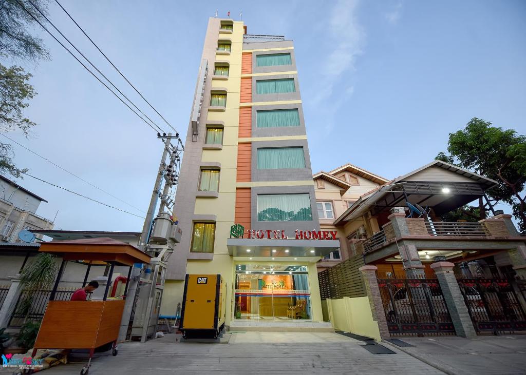 a tall building with a store in front of it at Hotel Homey Mandalay in Mandalay