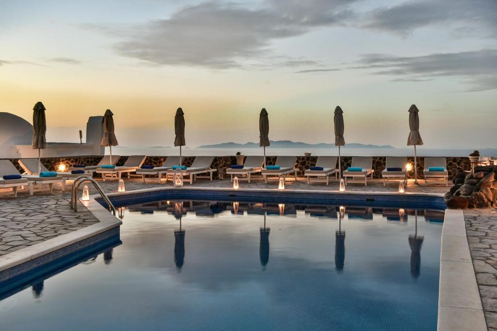 una piscina del resort con sedie a sdraio e ombrelloni di Agnadi View Villa a Oia
