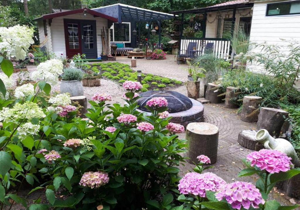 een tuin met roze bloemen en een vuurplaats bij Kunstenaars Boshuisje Veluwe in Hoenderloo