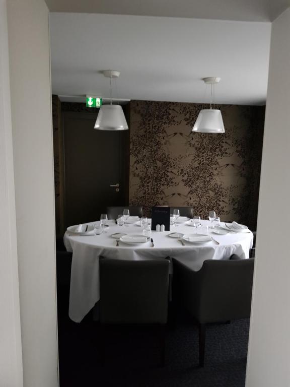 a room with a table with white tables and chairs at Logis Hôtel A la Bonne Auberge in Laval