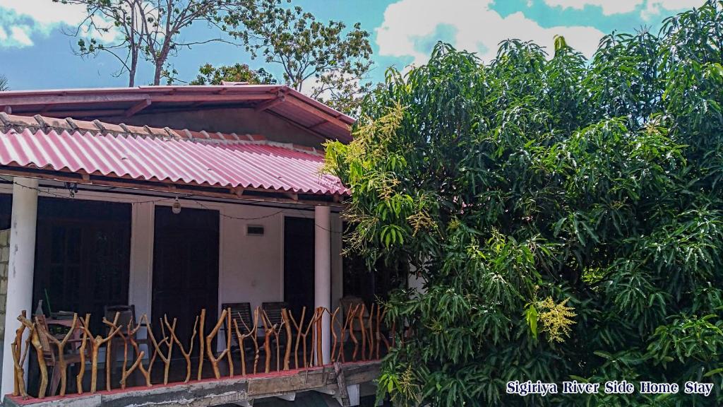 a house with a balcony next to some trees at Sigiriya River Side Home Stay in Sigiriya