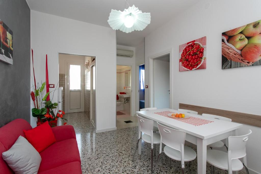 sala de estar con mesa blanca y sofá rojo en Appartamenti Bedin, JESOLO LIDO, en Lido di Jesolo