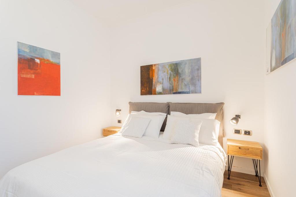 una camera da letto con un letto bianco e due dipinti alle pareti di RosArt House by Rent All Como a Como