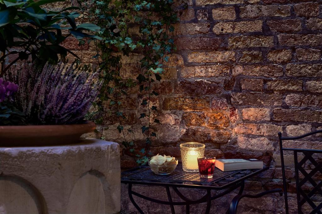 a table in front of a brick wall with a book and candles at Hotel Pausania in Venice