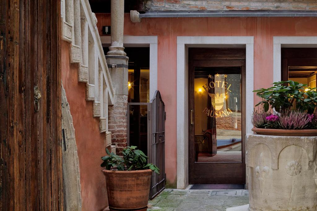 a pink building with potted plants in front of a door at Hotel Pausania in Venice