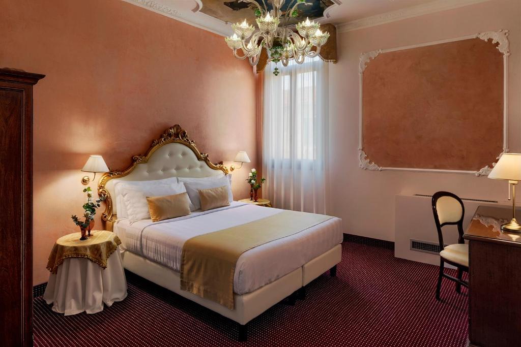a bedroom with a large bed and a chandelier at Hotel Pausania in Venice