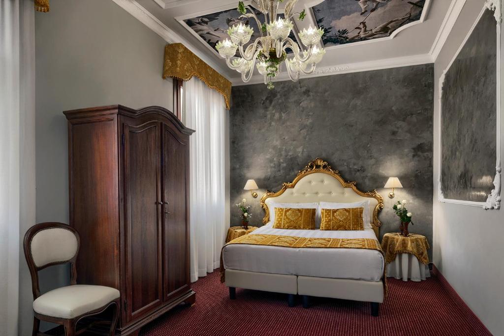 a bedroom with a king sized bed and a chandelier at Hotel Pausania in Venice