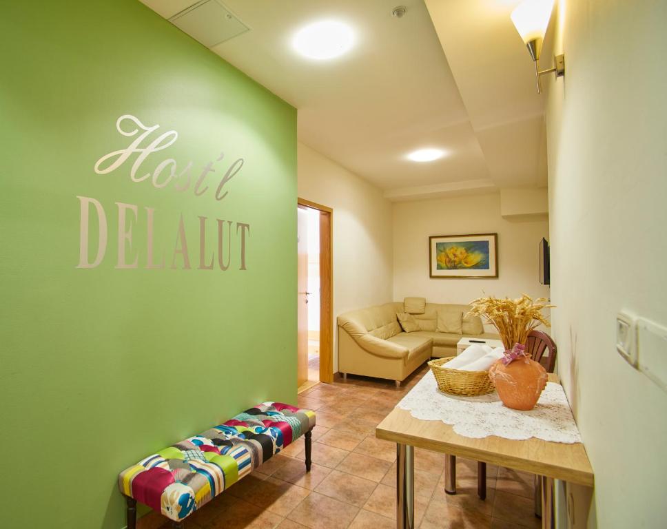 a living room with a green wall with a couch at Hostel Delalut in Ravne na Koroškem